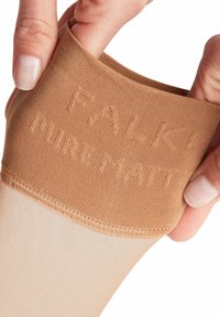 Rajstopy w kolorze nude z teksturowanym pasem w talii, na którym wytłoczono "FALKE PURE MATT". Część nogawki jest gładka i półprzezroczysta.