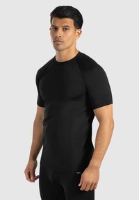 Schwarzes, kurzärmeliges Sportshirt mit tailliertem Design und Raglanärmeln. Glatter, dehnbarer Stoff mit minimal sichtbarer Markenkennung.