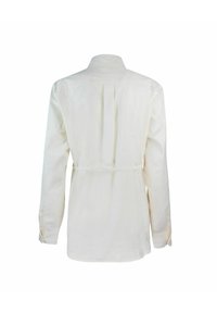 Camicia a maniche lunghe in tessuto crema con colletto, dettaglio della piega sul retro e cintura da annodare in vita. Tessuto liscio e vestibilità comoda.