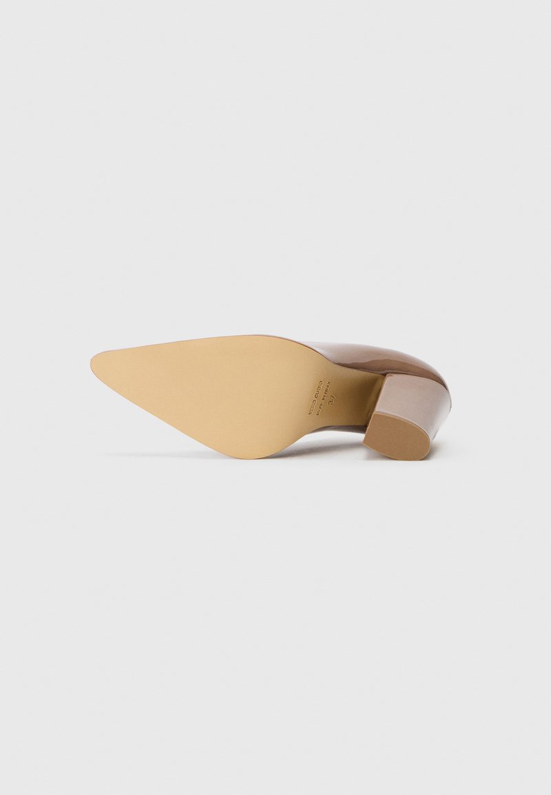 Chaussure à talon haut marron avec un bout pointu et un talon carré ; dessus en cuir lisse et semelle beige clair. Branding minimal visible sur la semelle.