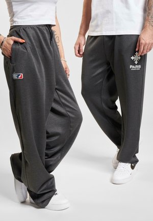 Szare, luźne joggery z miękkiego materiału. Zawierają naszywkę z logo i tekstowe detale, mają elastyczny pas i boczne kieszenie.