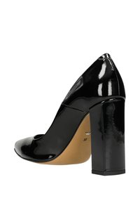 Scarpa con tacco alto in pelle laquered nera, con punta arrotondata, tacco quadrato spesso e dettagli ritagliati sul lato. Taglia 37 indicata all'interno.