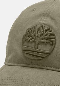 Khaki Kappe mit einem gestickten Baumlogo. Der Stoff hat eine strukturierte Webart, mit einem gebogenen Schirm und Belüftungsöffnungen.