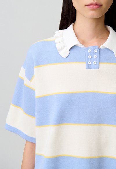 Polo in maglia con strisce blu, bianche e gialle. Presenta un colletto bianco arricciato e una patta con cinque bottoni.
