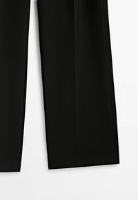Pantalon de costume noir à coupe droite, présenté du genou vers le bas sur fond blanc.