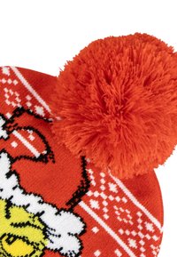 Rode gebreide beanie met een donzige oranje pompon, voorzien van een speelse ontwerp met witte en zwarte accenten, inclusief een karakterillustratie.