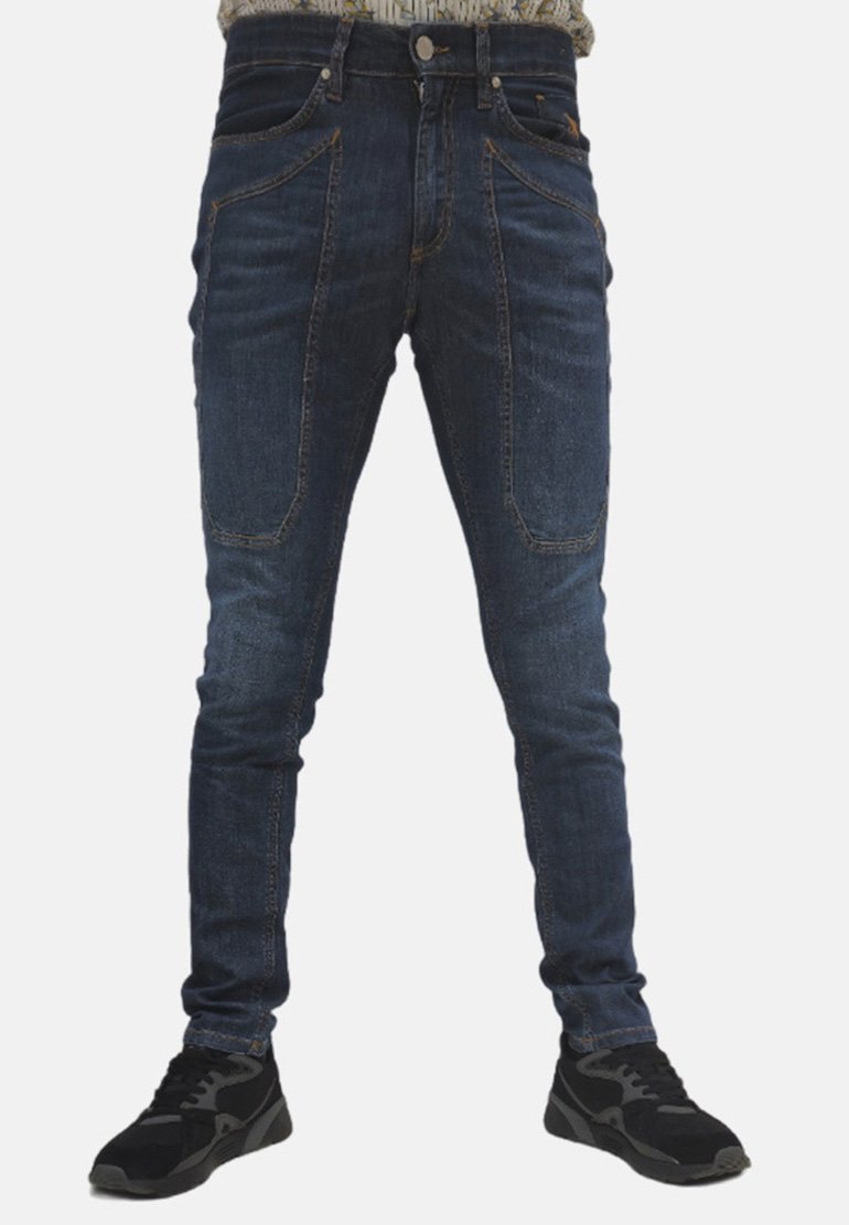 Jeans in denim blu scuro con vestibilità slim, caratterizzati da tasche frontali distintive e una texture liscia, abbinati a scarpe sportive nere.