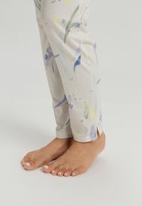 Lichte, gemusterde broeken in beige met aquarelachtige spetters in blauw, geel en groen; met zijsplitten aan de zoom.