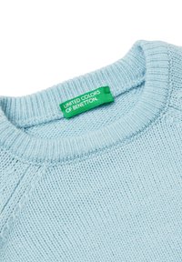 Jasnoniebieski sweter dzianinowy z okrągłym dekoltem i ściągaczami. Posiada zieloną metkę z napisem "United Colors of Benetton".