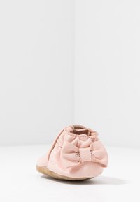 Myk rosa skinn slip-on sko med en samlet kant og sløyfedetalj bak. Suede såle gir tekstur og fleksibilitet for komfort.