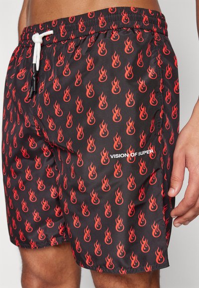 Pantaloni da nuoto neri con un motivo a fiamma rossa ripetuto, dotati di una cintura elastica con un laccio bianco e il logo "VISION OF SUPER".