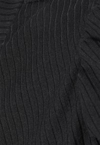 Tissu noir à côtes avec une surface texturée, présentant des lignes verticales créant un motif ondulé, doux au toucher.