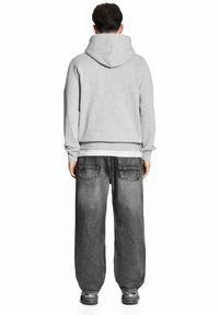 Szary hoodie z kapturem i sznurkiem, dopasowane mankiety, zestawiony z luźnymi, wyblakłymi czarnymi dżinsami z tylnymi kieszeniami.