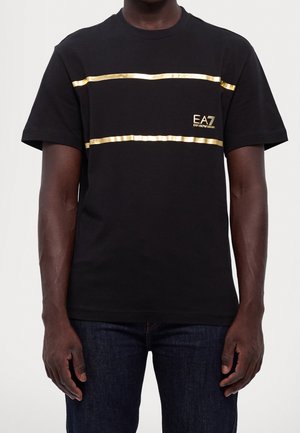 Sort bomulds t-shirt med to vandrette guldstriber og et lille broderet logo på venstre bryst. Korte ærmer og rund halsudskæring.