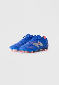 Blue soccer cleats with a textured upper, silver accents, and multi-colored studs (orange and gray) for traction on the field.