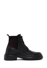 Botas negras de tobillo con un acabado en cuero suave y paneles laterales de malla. Presentan una suela de goma gruesa y cordones en la parte frontal.