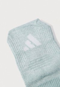 Αθλητική κάλτσα ανοιχτού μπλε χρώματος με υφασμένο ανάγλυφο σχέδιο, που διαθέτει λευκό λογότυπο και ριγέ διακοσμητικά κοντά στον αστράγαλο.