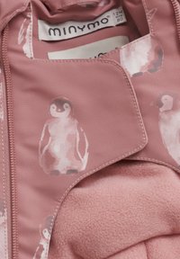 Fleece-fôret lyserød jakke med pingvinprint, der har et glat yderlag, lynlås lukning og en blød inderside. Størrelsesmærket er synligt indeni.
