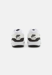 Sneakers Nike Air albe cu un accent negru. Proiectate cu un superior din textile neted și o talpă căptușită, având detalii cu logo pe călcâi.