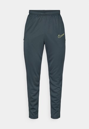 Nike sportieve broek, donkergrijs, tapered fit, elastische tailleband, twee zijzakken, gele logo-detail op de bovenste linker dij.