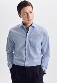 Camicia button-up azzurro chiaro con taschino sul petto, maniche lunghe e colletto classico, realizzata in un mix di cotone testurizzato.