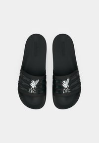 Fekete papucs több vízszintes pánttal, texturált felülettel és fehér Liverpool F.C. logóval a felső pánton.