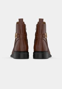 Leren enkellaarzen in donkerbruin, met een ronde neus, zwarte blokhak, zijritsen en een decoratieve gouden gesp. 