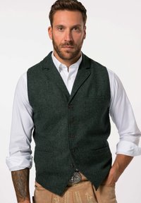 Grüne Fischgrätweste mit Reverskragen, fünf vorderen Knöpfen und zwei Seitentaschen, kombiniert mit einem weißen Hemd und beigen Hosen.
