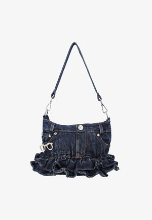 Rifľová kabelka štýlovo vytvorená ako sukňa s volánovým lemom, prednými vreckami, detailom gombíka a malým dekoratívnym príveskom okuliarov na bielom pozadí.