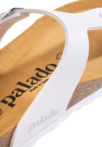 Hvide flip-flop sandaler med blødt læderrem, kork fodseng og struktureret gummisål. 'Palado' branding synlig på indersålen.