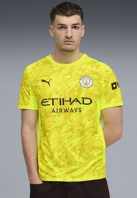 Gul fotbollströja med strukturerat mönster, svart logotyp och texten "ETIHAD AIRWAYS". Kortärmad och design med rund hals.