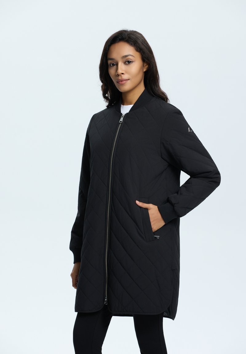 Veste noire matelassée avec zip, poches latérales et col côtelé. Présente une coupe longue et droite ainsi qu'une finition lisse et mate.