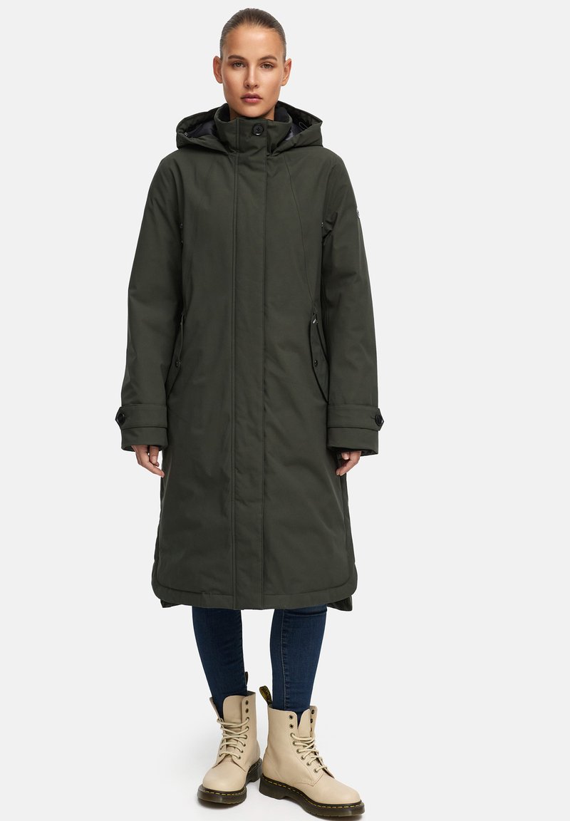 Langer olivgrüner Parka mit Kapuze, mit Reißverschluss, Seitentaschen und glatter Textur. Getragen über Jeans und beigen Schnürstiefeln.