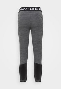 Szare legginsy z czarnym pasem w talii ozdobionym logo „NIKE”. Materiał o fakturze oraz czarne akcenty na dolnych partiach nóg. Dopasowany krój.