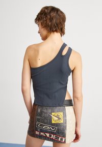 Top corto grigio a costine con una spalla sola e dettaglio ritagliato, abbinato a una gonna di jeans grafica multicolore.
