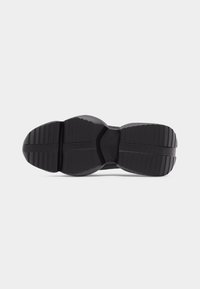 Μαύρη σόλα παπουτσιού από καουτσούκ με βαθιές οριζόντιες και κάθετες αυλακώσεις για καλύτερη πρόσφυση, εμφανίζεται πάνω σε απλό λευκό φόντο.