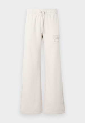 Light beige sweatpants with a drawstring waist, wide leg design, and a small white printed logo on the left thigh. Soft cotton material.