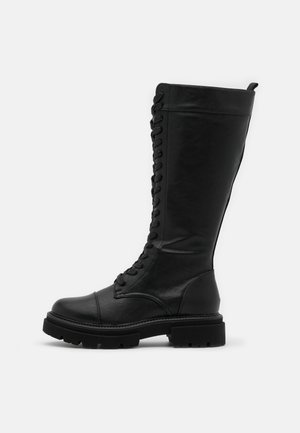 Bottes hautes jusqu'au genou noires à lacets en cuir lisse, avec une semelle en caoutchouc épaisse et un renfort d'orteil pour la durabilité.
