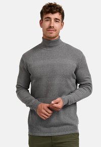 Grå strikket genser med høy hals, med teksturerte striper og en tettsittende design. Har ribbestrikkede mansjetter og kant, laget av et mykt materiale.