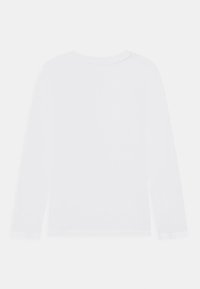 Biała koszulka z długim rękawem wykonana z miękkiej bawełny, z okrągłym dekoltem i prostym przeszyciem wzdłuż brzegów oraz mankietów.