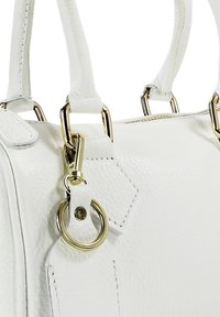 Witte leren handtas met goudkleurige accenten, waaronder een clip en ringdetail. Getextureerd oppervlak met zichtbare stiknaden.