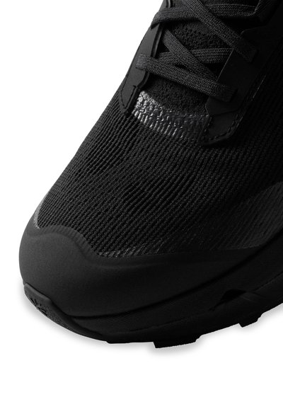 Baskets de sport noires avec une tige en tissu texturé, un embout en caoutchouc lisse et des lacets plats. Présente un design ton sur ton pour une apparence élégante.