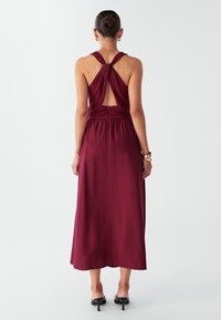 Burgundiapunane maxi-kleidi keeratud seljaga, elastse vöökohaga ja siledast kangast. Omadusteks on avausega seljaosa ja voolav seelik.