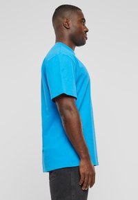 Short-sleeve, round-neck T-shirt in bright blue cotton. Regular fit with a smooth texture. Visible stitching along the shoulder seams.