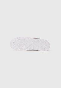 White rubber sneaker sole with textured patterns and a circular accent. Features grooves for traction and a flat profile. Clean design.