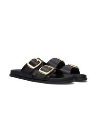 Black leather slide sandals featuring two oversized gold buckles, flat rubber sole, and open-toe design with a smooth texture.