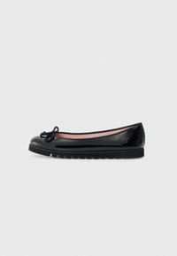 Ballerine en cuir verni noir avec un bout rond, détail de nœud sur le dessus, et une semelle en caoutchouc texturé. L'intérieur présente un revêtement rose.