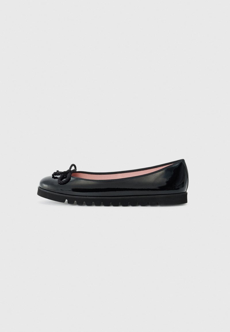 Ballerine en cuir verni noir avec un bout rond, détail de nœud sur le dessus, et une semelle en caoutchouc texturé. L'intérieur présente un revêtement rose.