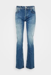 Vaqueros de mezclilla de corte acampanado en azul claro, con un diseño clásico de cinco bolsillos, que presentan un cierre de cremallera y un leve desvanecimiento a lo largo de las piernas.