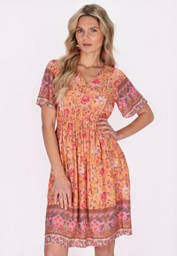 Bloemjurk met een oranje basis en roze en rode bloemen, een V-hals, korte mouwen en een getailleerde taille. De zoom heeft verfijnde details.